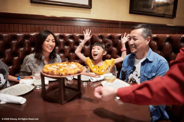 A family sitting in a leather booth at Trattoria al Forno as a pizza is served to their table