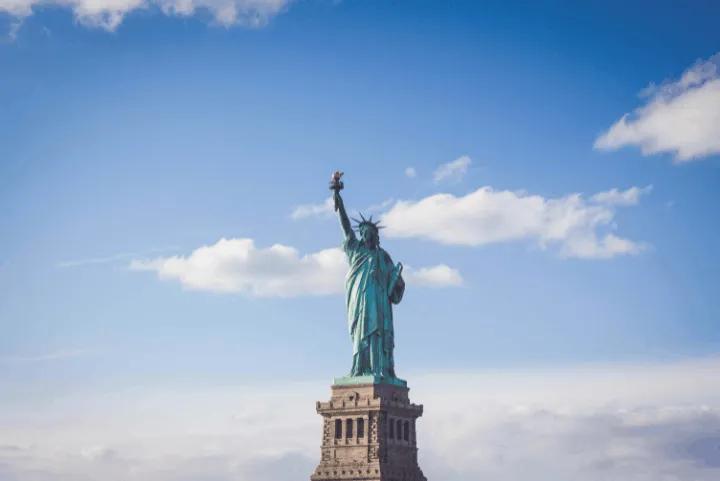 The Statue of Liberty standing tall against a blue sky with scattered clouds