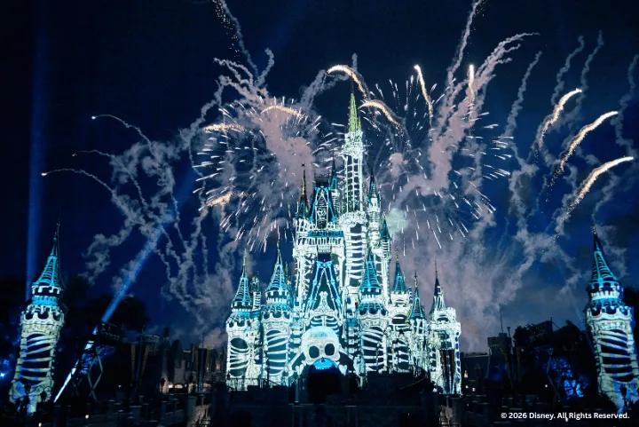 Fireworks exploding over Cinderella Castle decorated with a skull projection