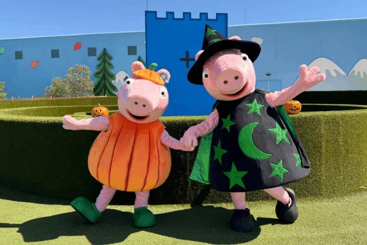 Peppa Pig and George dressed in Halloween costumes posing outdoors