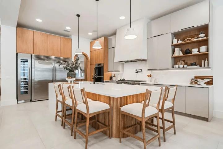 Modern luxury kitchen in an Orlando villa featuring a large island with seating, natural wood cabinetry, and stainless steel appliances