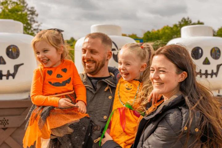 A smiling family posing in front of Lego skeleton heads during Brick or Treat at Legoland Windsor
