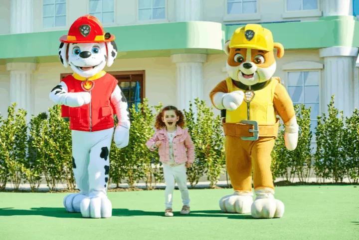 A young girl walking with PAW Patrol mascots Marshall and Rubble
