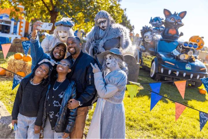 A family taking a selfie photo with costumed Alton Ancestors characters outdoors