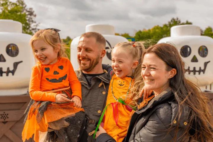 A family with children dressed in pumpkin costumes smiling at the LEGOLAND Brick-or-Treat event