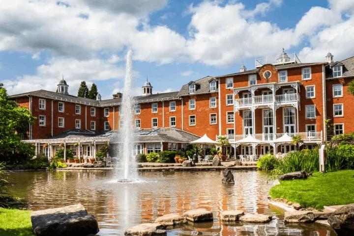 Exterior view of the Alton Towers Hotel featuring a lake and fountain in the foreground
