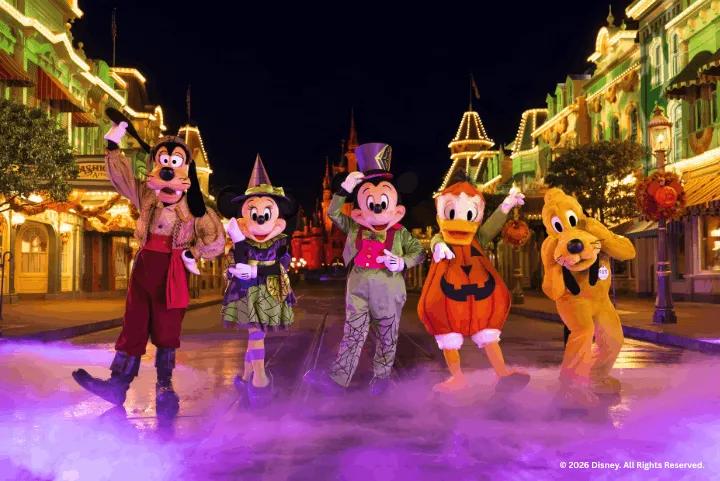 Mickey, Minnie, Donald, Goofy, and Pluto in Halloween costumes on Main Street, U.S.A. at night