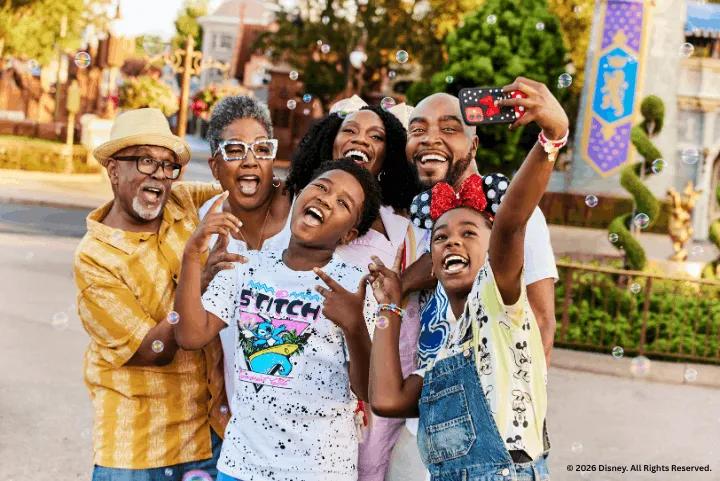 A joyful multi-generational Black family taking a group selfie with bubbles floating around them at Disney's Magic Kingdom Park