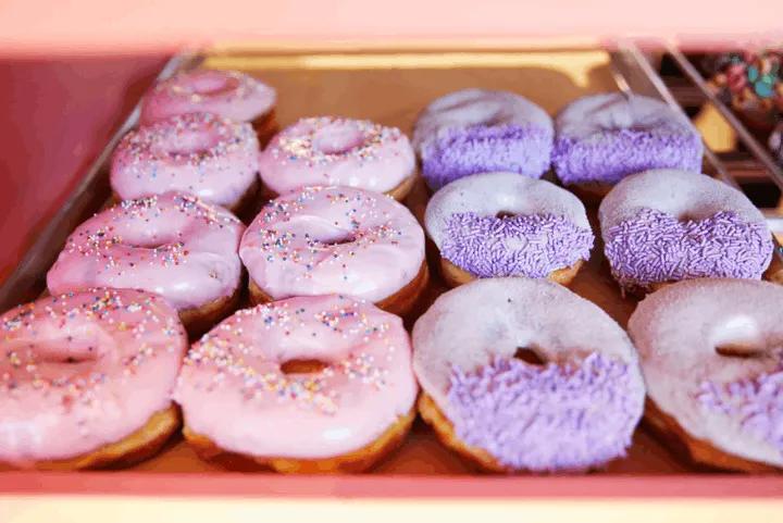 Tray of pink and white iced doughnuts with sprinkles from Voodoo Doughnut at Universal CityWalk