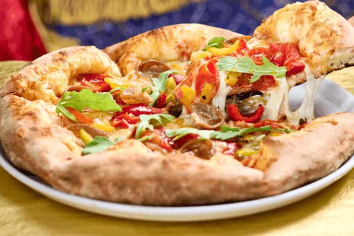 A slice of Harvest Moon pizza with fresh toppings being lifted from a plate at Pizza Moon in Universal Epic Universe