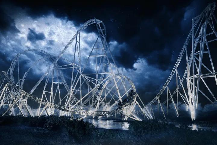 A large white roller coaster illuminated against a starry night sky