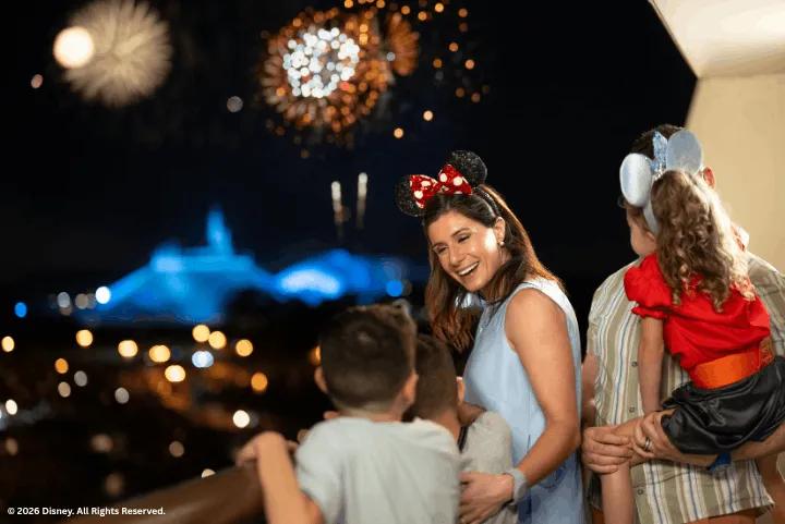 A family on a balcony watching fireworks over Space Mountain at night