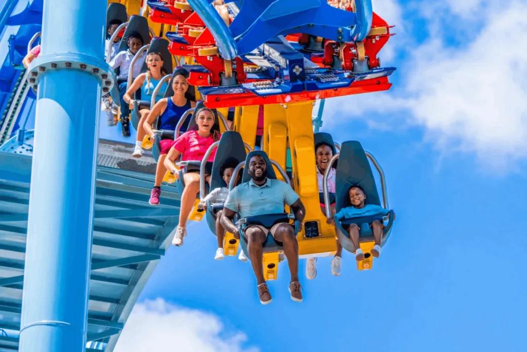 Riders enjoying the Phoenix Rising suspended roller coaster against a blue sky