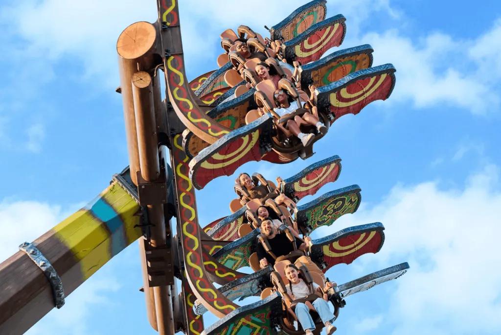 People swinging on the Dragon Racer’s Rally attraction against a blue sky