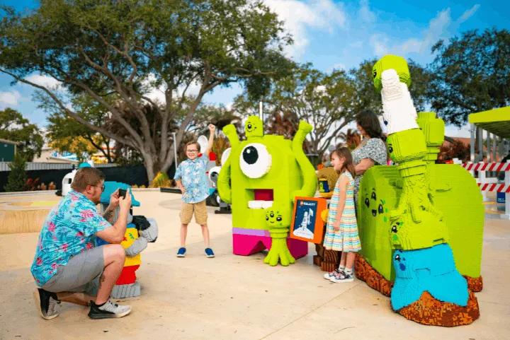 A family taking a picture with large green alien LEGO models in the LEGO Galaxy area