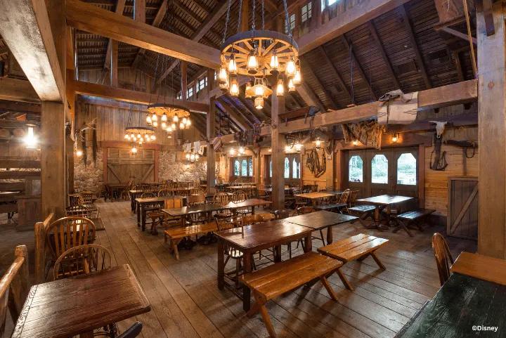 Rustic barn-style dining area featuring wooden tables, benches, and wagon wheel chandeliers