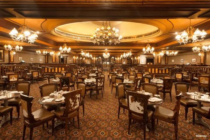 Western-style dining room with dark wood paneling, chandeliers, and cowhide-backed chairs