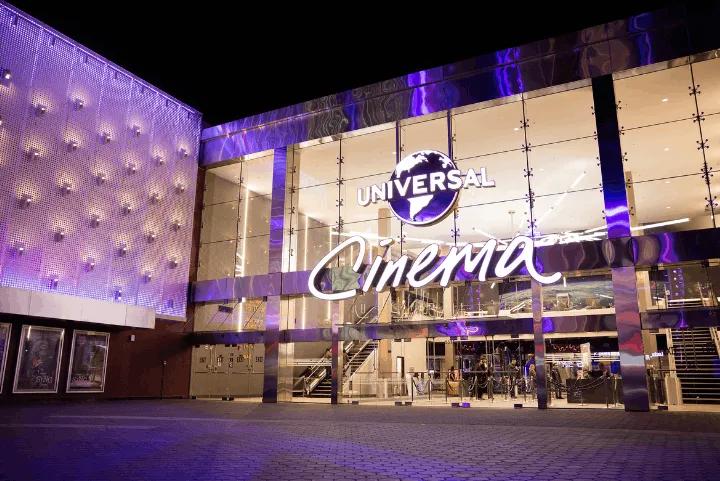 The brightly lit exterior of the Universal Cinema building at night