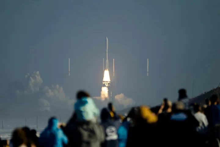 A crowd of spectators watching a distant rocket launch