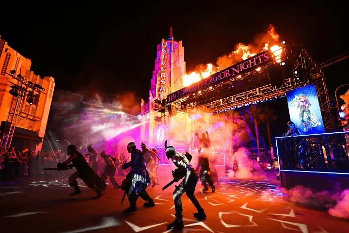 Costumed characters performing amid fog, fire effects, and bright lights in the Fortnitemares scarezone at Halloween Horror Nights