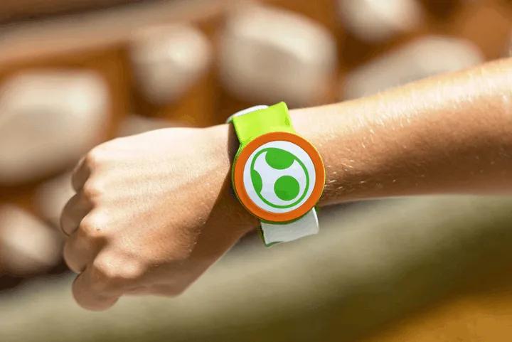 A close-up of a guest wearing a green Yoshi Power-Up Band on their wrist