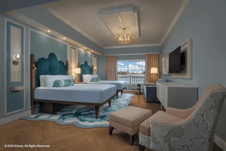 A blue-themed hotel room featuring two beds, a lounge chair, and a balcony