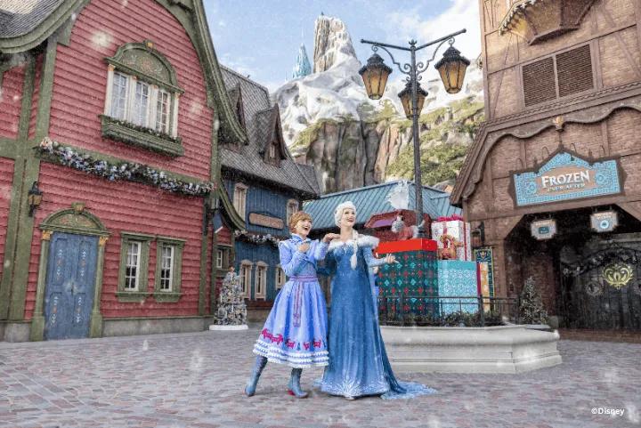 Anna and Elsa standing together in a snowy village square