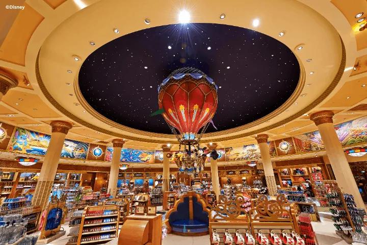 Interior of a large Disney merchandise store featuring a hot air balloon hanging from a starry ceiling dome