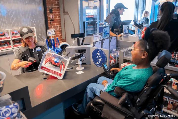 A young guest in a wheelchair purchasing a toy at a store checkout counter