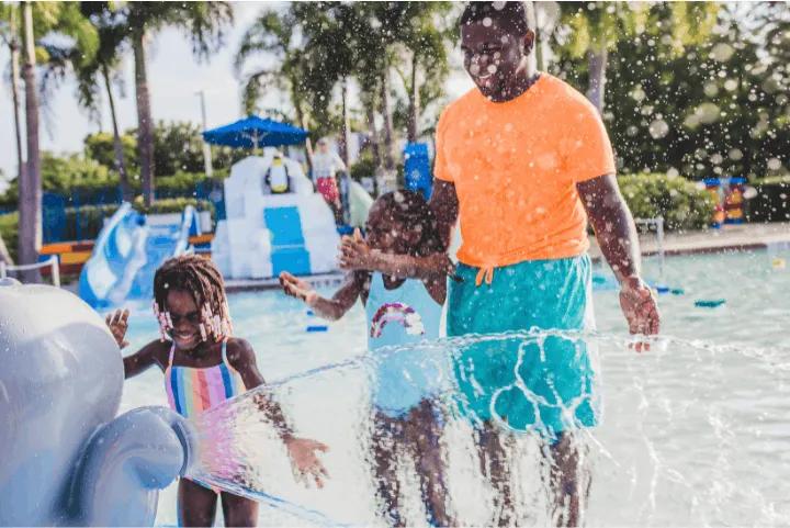 Alt Text: A father and two children playing in the water at Splash Safari