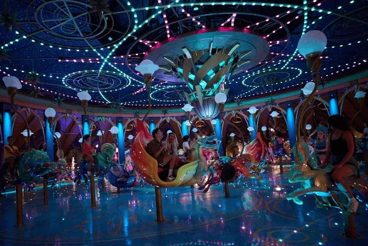 Guests riding a brightly lit, celestial-themed carousel