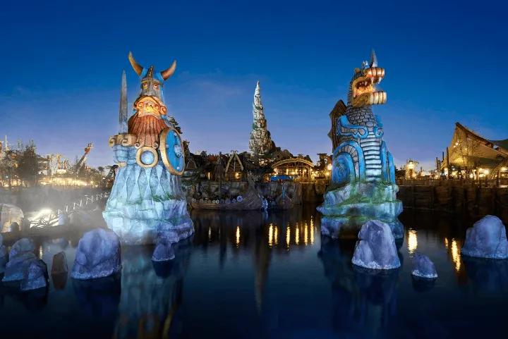 Large illuminated Viking and dragon statues in a body of water at night