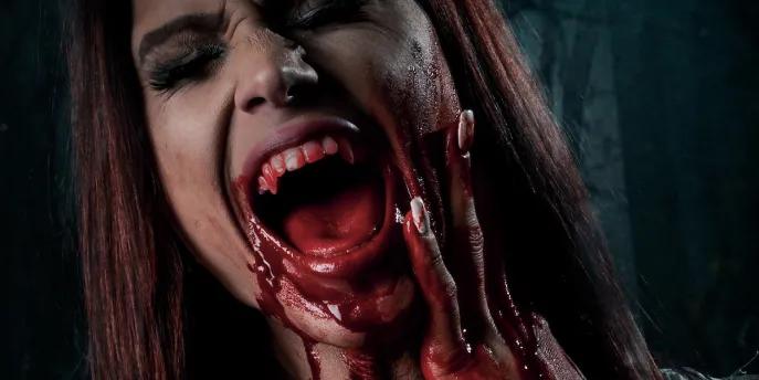 A woman screaming and holding her face with blood on her hands and chin