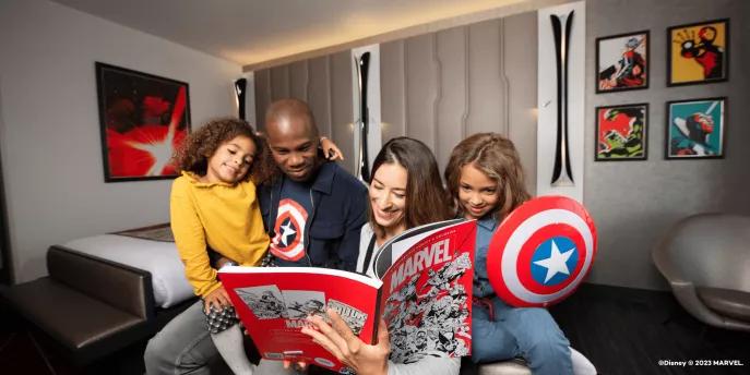 A family of 4 sat on a bed reading a Marvel comic 