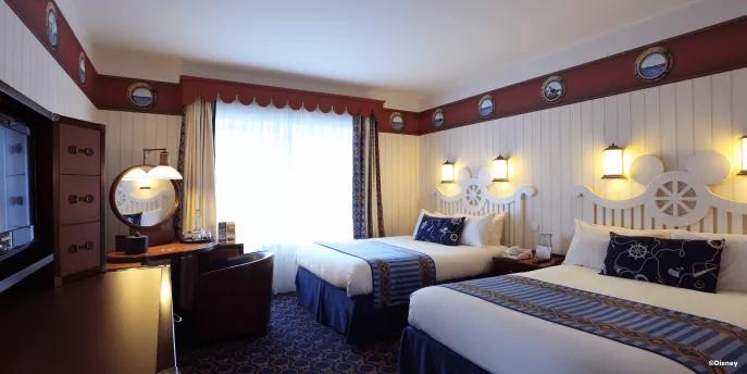 A nautical themed hotel room with two double beds and a dresser