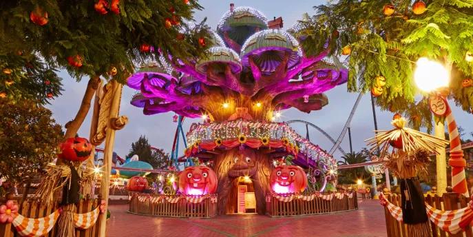 A large cartoon style tree decorated with sparkling lights and pumpkins