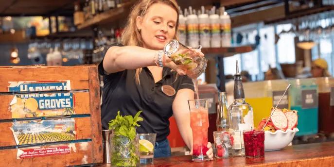 Flavours of Florida at Disney Springs A woman pouring colourful drinks behind a wooden bar