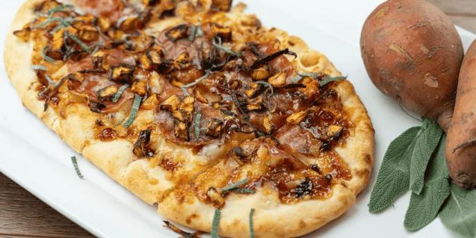 A long pizza topped with autumnal ingredients