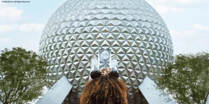 A young girl wearing Minnie ears facing towards Spaceship Earth at EPCOT