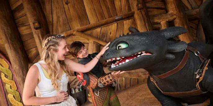 Toothless and Hiccup with guest - Isle of Berk Black dragon with more open meeting a guest who has her hand on Toothless' snout. Hiccup is behind consoling the dragon in his viking attire.