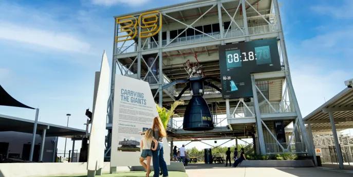 The Gantry at LC-39 A woman and young girl standing in front of a rocket experience at Kennedy Space Center