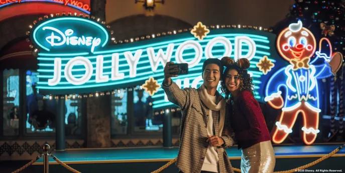 Disney Jollywood Nights at Disney's Hollywood Studios A couple taking a selfie in front of a neon sign for Disney Jollywood Nights