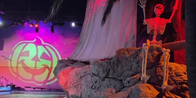 SEA LIFE Room decorated with prop skeleton on rocks, the sea below and a pumpkin projection.