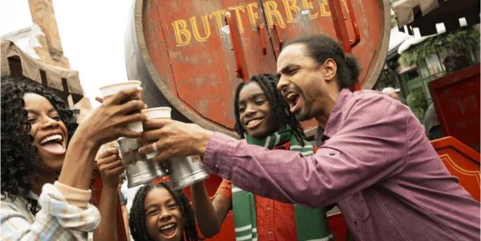 An excited family raising Butterbeer beverages in celebration, capturing an unforgettable and unique experience in The Wizarding World of Harry Potter at Universal Orlando Resort.