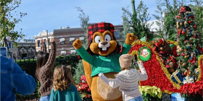 Children waving at a friendly squirrel character, surrounded by Christmas decorations and red poinsettias, capturing a joyful holiday season moment and a memorable experience in Orlando.