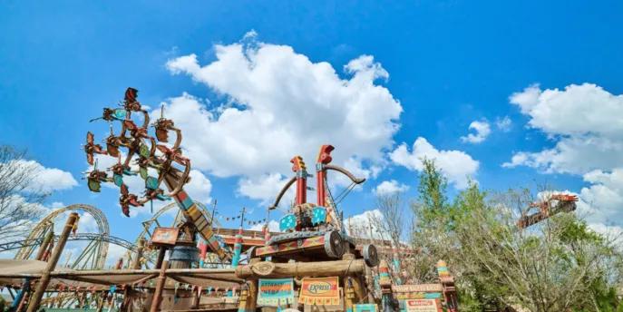 A wide view of the colorful How to Train Your Dragon – Isle of Berk land at Universal Epic Universe, featuring the towering Dragon Racer's Rally ride structure against a bright blue sky.