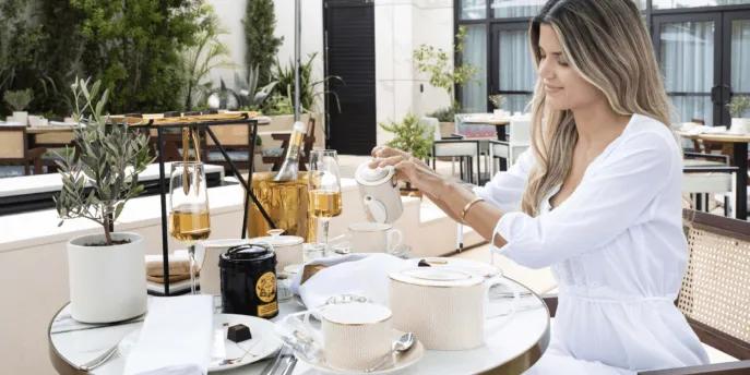 Woman dining outside on terrace pouring a drink