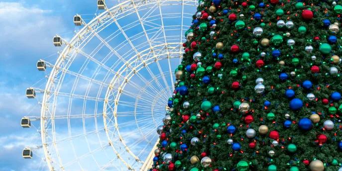 The orlando eye with a christmas tree in front of it.