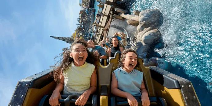 Riders laughing and screaming as their coaster splashes through water on Hiccup's Wing Gliders, Isle of Berk