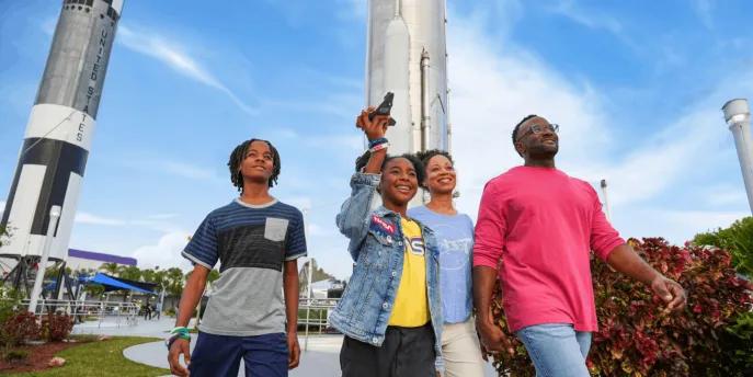 A family walking past large rockets at the Kennedy Space Center Rocket Garden